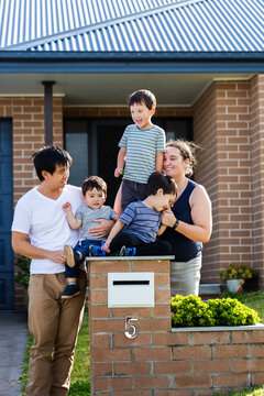portrait of mixed race Chinese Australian family outside home with kids sitting on mailbox