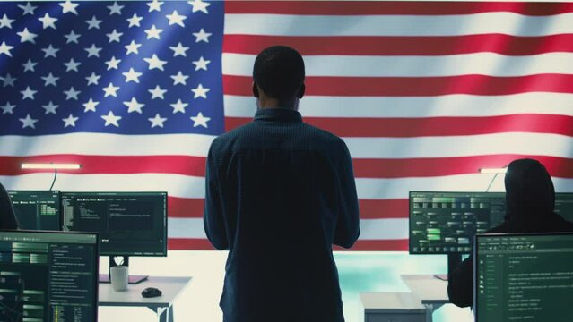 Cyber defense experts in a governmental tech room with the American flag. Working on secure computing, digital forensics and cyber operations to protect and maintain cyber safety. Camera B.