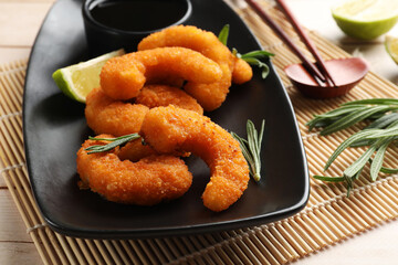 Tasty breaded fried shrimps served on light wooden table, closeup