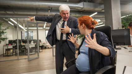 Elderly Caucasian man shouts at pregnant submissive woman and points to the door. 