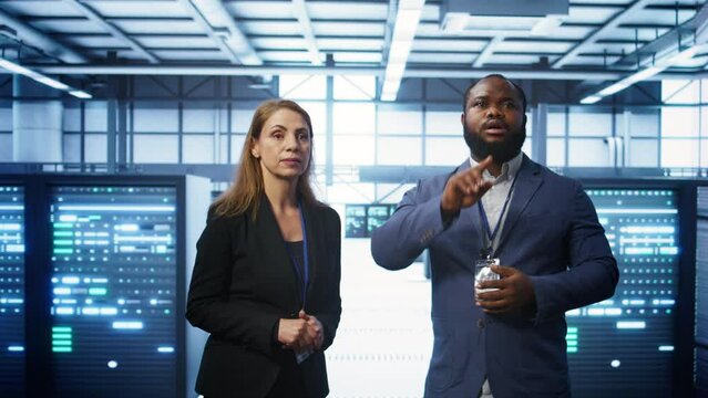 Teamworking technicians in high tech data center workspace looking at hologram visualization. Programmer and colleague working on securing server room hardware using AR tech, camera B