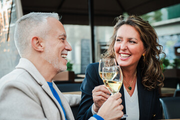 Mature couple toasting white wine glasses on a bar terrace. Middle aged married people drinking...