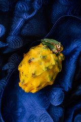 yellow whole dragon fruit, dragonfruit, pitaya on cobalt blue material