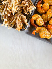 Breaded fried shrimp and crispy enoki mushrooms on the table background. Copy space.