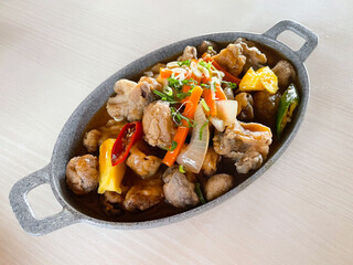 Sweet and sour sauce mushroom with chopped pepper and pineapple in a hot plate on table background.