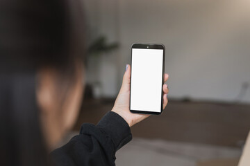 Young Woman Holding Smartphone with Blank White Screen in Modern Indoor Setting, Perfect for Mockups and Digital Content