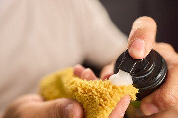 A man is cleaning the cars ceiling meticulously with a yellow cloth, focusing on detail