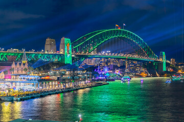 Obraz premium Colourful Light show at night on Sydney Harbour NSW Australia. The bridge illuminated with lasers and neon coloured lights Vivid Sydney Laser and Light Drone show