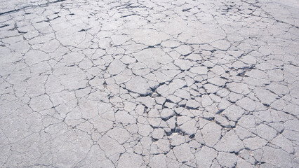 The old badly damaged concrete yard floor in car park area with many broken crack lines texture on surface