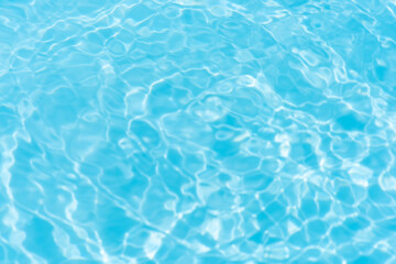 Blue water with ripples on the surface. Defocus blurred transparent blue colored clear calm water surface texture with splashes and bubbles. Water waves with shining pattern texture background.