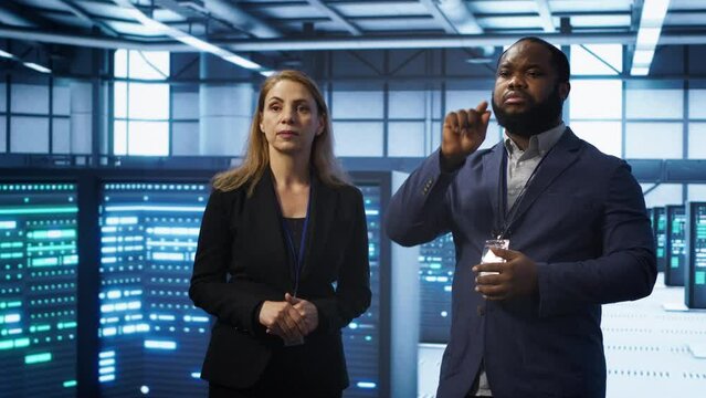 Teamworking technicians in high tech data center workspace looking at hologram visualization. Programmer and colleague working on securing server room hardware using AR tech, camera A