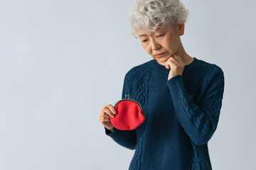 財布を持って悩むシニア女性