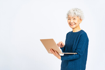 笑顔でノートパソコンを使うシニア女性