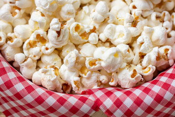 Close-up of salty popcorn in a bowl with red and white checkered fabric. Typical food for the São...