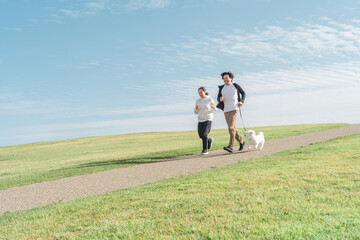 公園で犬の散歩をする家族・夫婦・カップル・男女（走る・ジョギング・ランニング）

