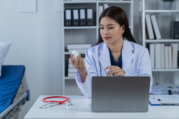 A photograph of a female doctor sitting at her desk in an office.