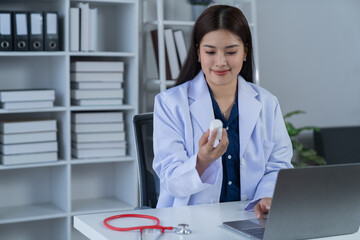 A photograph of a female doctor sitting at her desk in an office.