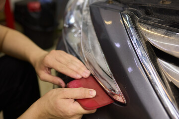 Person using a machine to polish automotive lighting on a car headlight