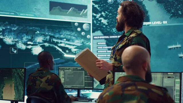 Army major reads operation details from a case file in a control center military headquarters, manages personnel and resources for logistical or operational missions. Task force command. Camera A.