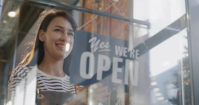 Slow motion of cheerful waitress changing Sorry we are closed to Yes we are open sign on cafe door. Business and eating out concept.