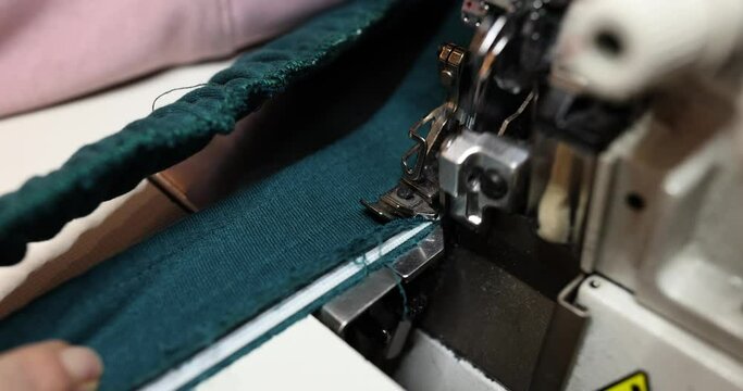 Dressmaker expertly stitches textile with overlock machine