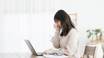 パソコン作業に目の疲れを感じる女性