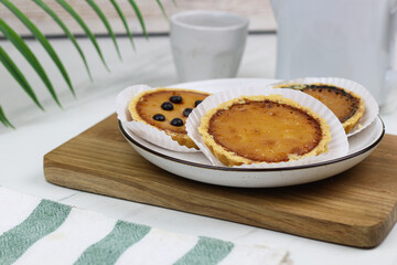 Pie Susu Bali or popular egg tart from Bali, Indonesia, served with various topping original and chocolate. Tea time concept with marble background.