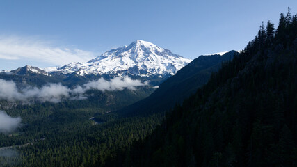 Fototapeta premium Snow-Capped Mountain Overlooking Forested Valley with Clouds