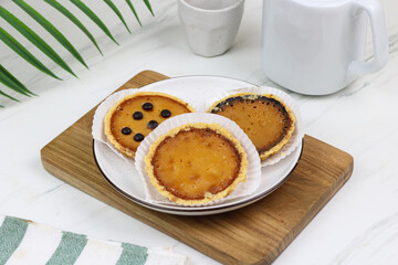 Pie Susu Bali or popular egg tart from Bali, Indonesia, served with various topping original and chocolate. Tea time concept with marble background.