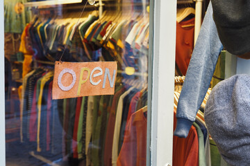 A sign indicating that a vintage clothing shop is open, located inside a clothing store