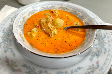 Closeup on an homemade lobster bisque soup served in vintage porcelain plates. Retro, old fashioned style.  