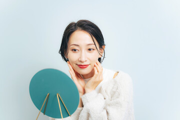 鏡を見ながらお肌をチェックするミドル女性