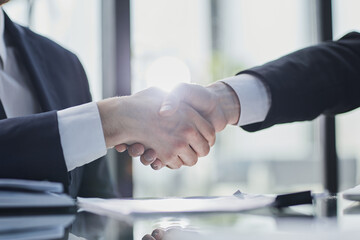 Close up of greeting handshake, young businessman hands shaking over conference table