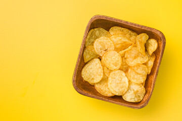 Crispy Potato Chips in bowl on Yellow Background. Top view.