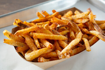 A closeup view of a tray of seasoned French fries.