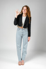 Young Woman Giving Ok Sign on gray background