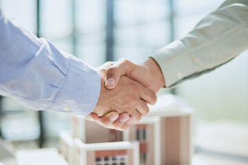 handshake against the background of a model of a house under construction. client and designer