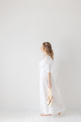 balerina walks with ballet shoes in hand in white studio © Cavan