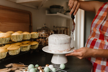 A woman decorating a birthday cake with white frosting