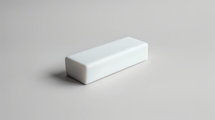 Minimalistic photo of a white rectangular eraser on a smooth, light gray surface. Ideal for educational and office-themed concepts.