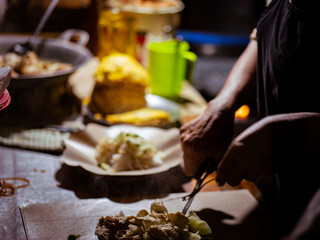 Indonesian street vendor preparing tahu tek. Tahu tek is one of the typical dishes of the city of Lamongan. consists of half-cooked fried tofu and lontong cut into small pieces with scissors.