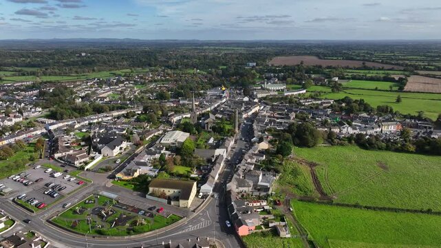 Kells, County Meath, Ireland, October 2023. Drone at a higher angle slowly orbits St Columba's Church of Ireland and Kells Round Tower on a sunny day with Church Lane in the foreground.