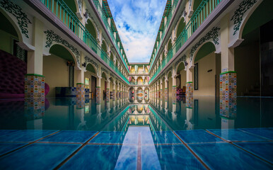 Fototapeta premium Beautiful courtyard featuring arched walkways and a reflective pool, showcasing intricate architectural details and colorful tiles.