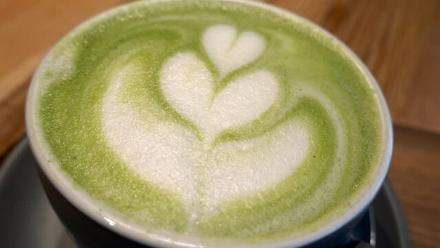 Close up of a a cup of matcha latte on a table at a cafe