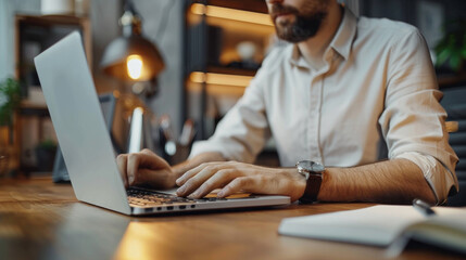 Obraz premium A man is typing on a laptop in a room with a desk and a clock on his wrist