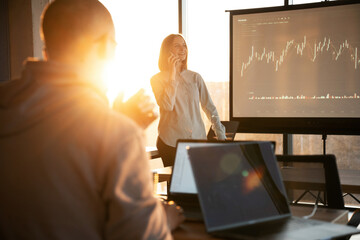 Guy is listening. Female business trainer is against projector with business data, teaching the man