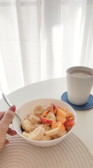 a bowl of oat meal and cup of coffee with milk on the white table in the morning
