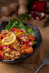 Rocca, beetroot, cherry tomato and pomegranate salad.
Healthy fresh fruit salad (rocket, orange, grapefruit, pomegranate, walnut) on black plate on dark background.