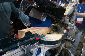 A worker cuts a wooden block using a circular saw.