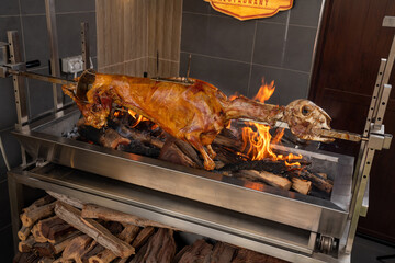Full whole lamb grilled with mandi and sauces and Salad. Lamb on a grilling stand with fire.